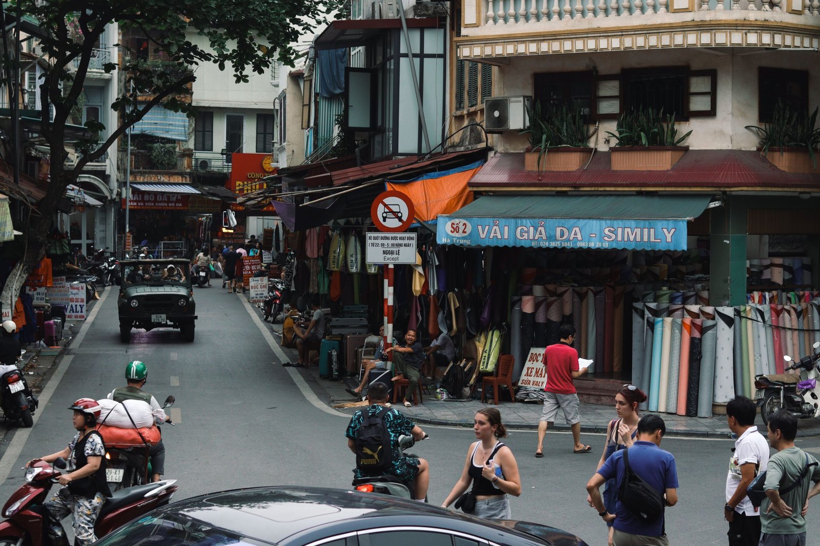 Home Vibrant street in Hanoi featuring locals shopping, motorbikes, and traditional buildings.