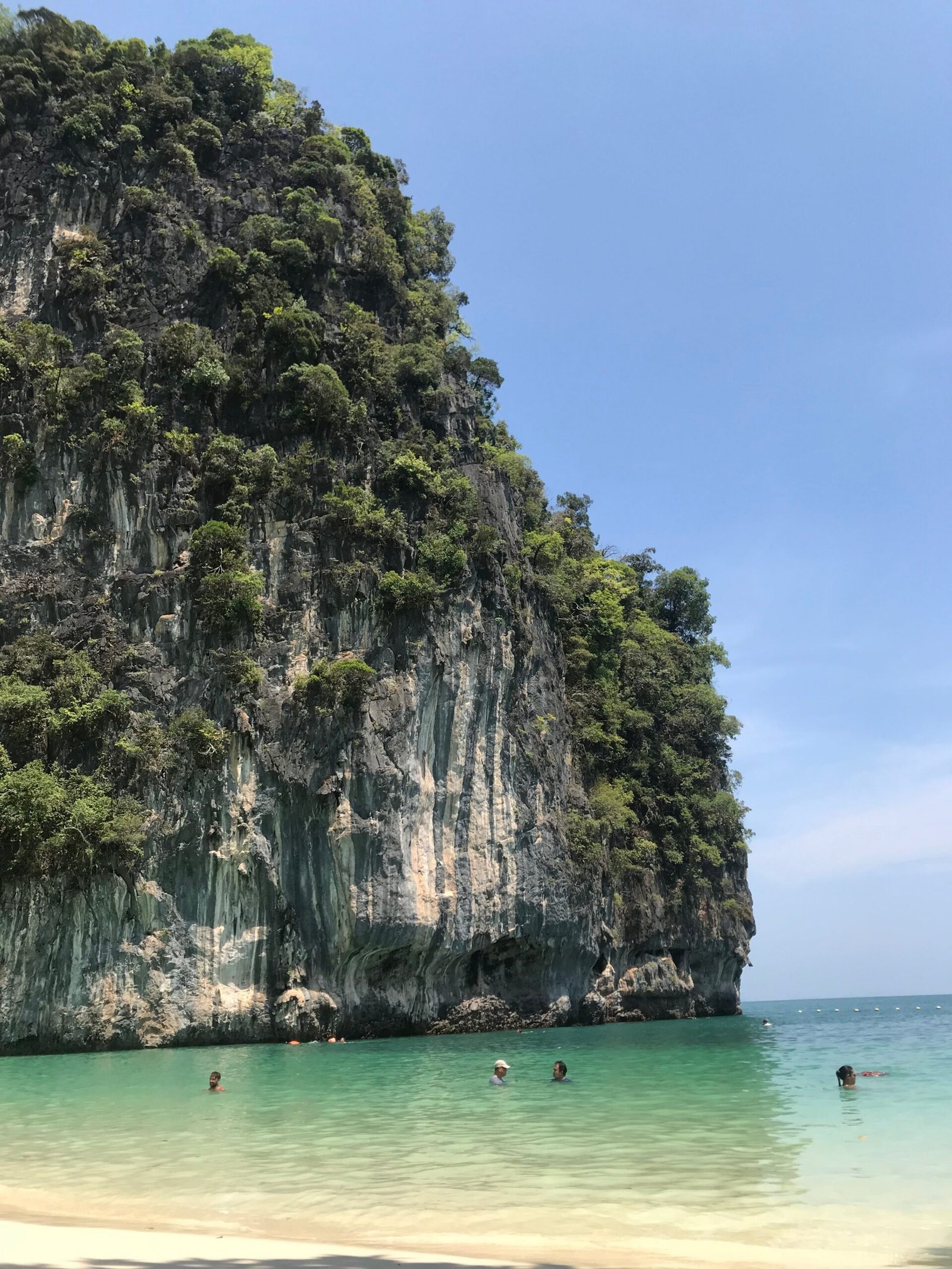 Home Scenic view of a serene beach with limestone cliffs and turquoise sea in Krabi, Thailand.