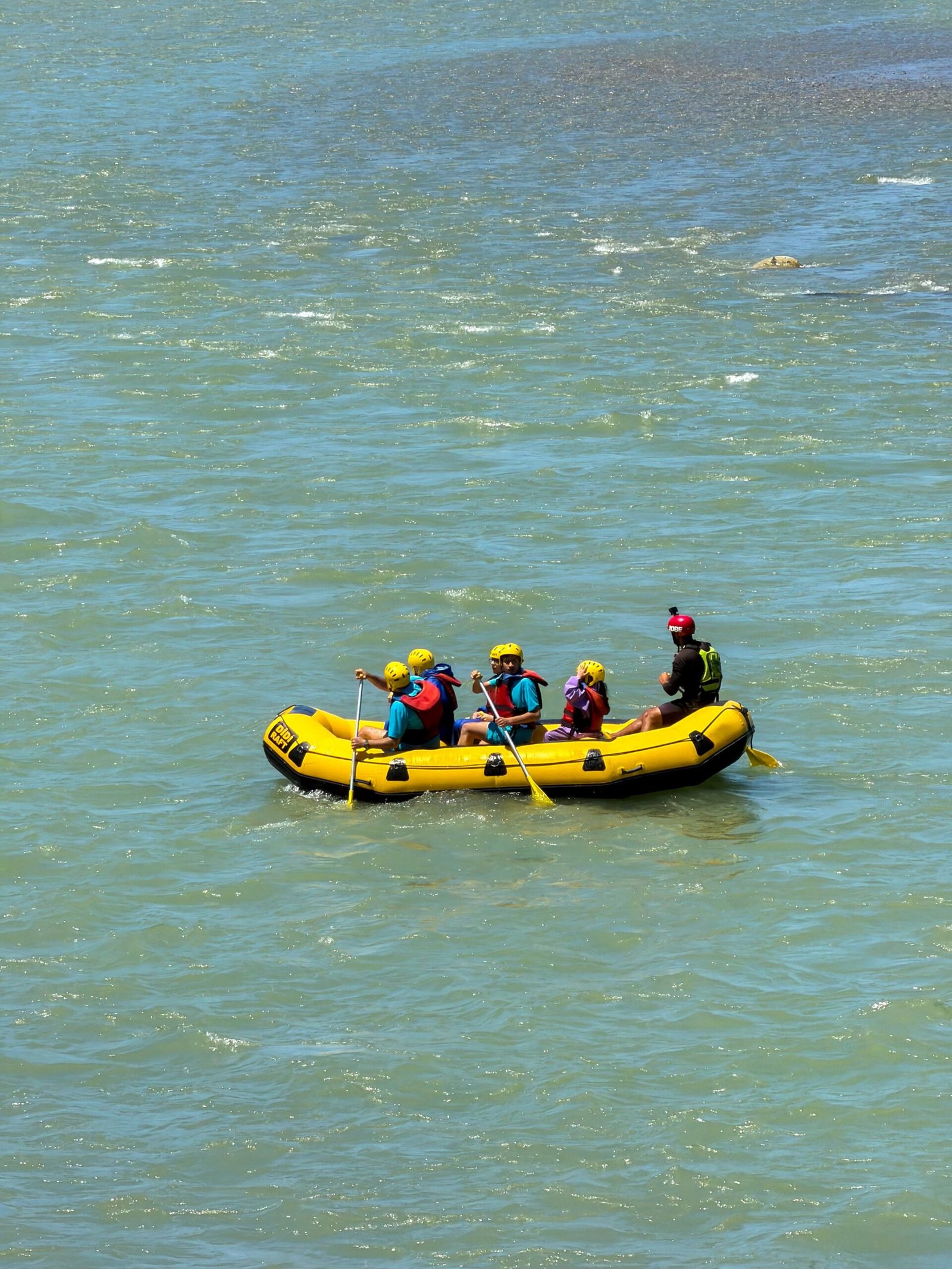 Home Group enjoying white-water rafting adventure on a river, showcasing teamwork and excitement.